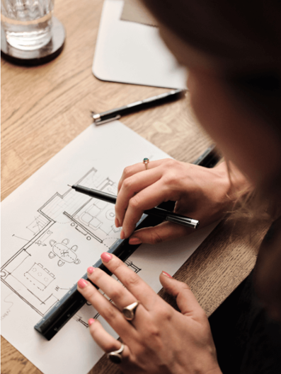 Contact-image d'une architecte qui réalise un plan au crayon sur une feuille de papier